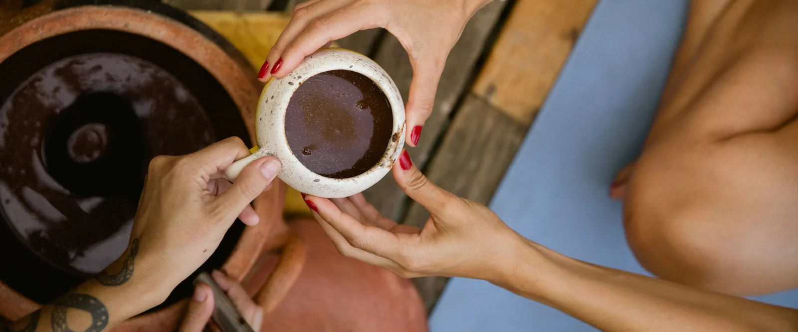A cup of ceremonial cacao passed from one pair of hands to another